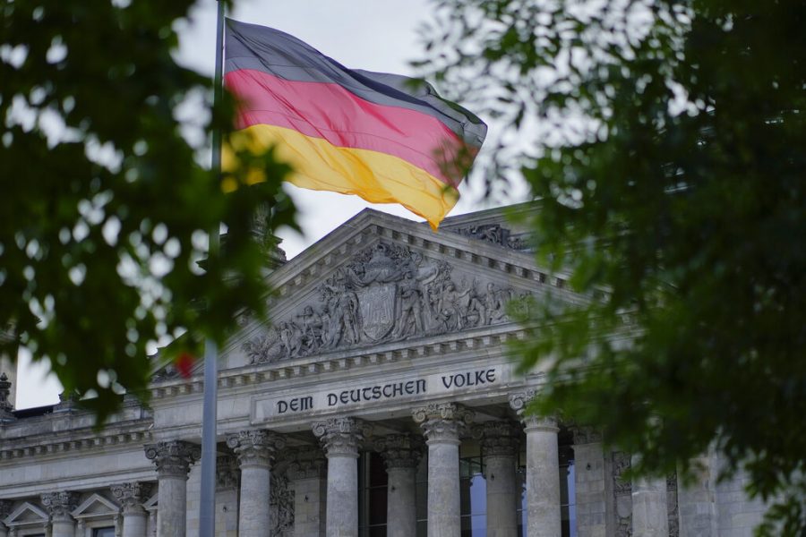The German national flag waves in front of the German parliament building, the Reichstag Building, with the slogan: To The German People in Berlin, Tuesday, Sept. 28, 2021. Germanys newly elected lawmakers are holding their first meetings as their parties digest the fallout of the election that reduced outgoing Chancellor Angela Merkels bloc to its worst-ever result and start the process of putting together a new government. (AP Photo/Markus Schreiber)